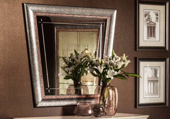 Καθρέφτης σε χρώμα γκρι και σχεδιασμένος με χάλκινες σφυρήλατες λεπτομέρειες.