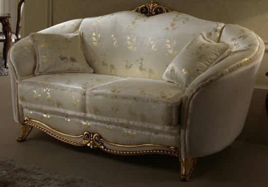 Καναπές διθέσιος ο οποίος είναι σχεδιασμένος σε χρώμα μπεζ και διακοσμημένος με χρυσά στοιχεία.