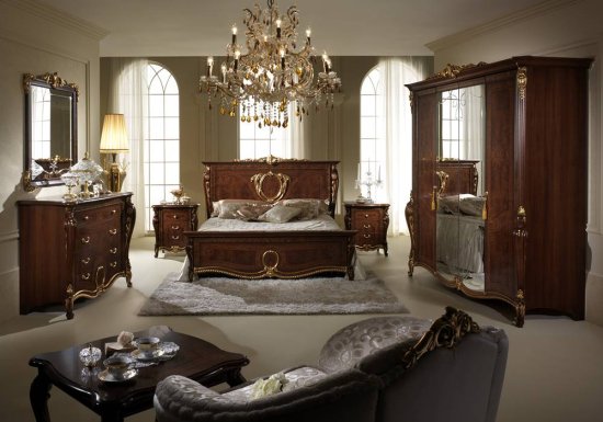 Κλασσικό καρυδί κρεβάτι το οποίο είναι διακοσμημένο με χρυσή κορώνα.