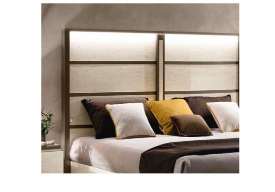 Κρεβάτι το οποίο είναι σχεδιασμένο σε χρώμα εκρού και διακοσμημένο με καφέ μεταλλικές λεπτομέρειες.