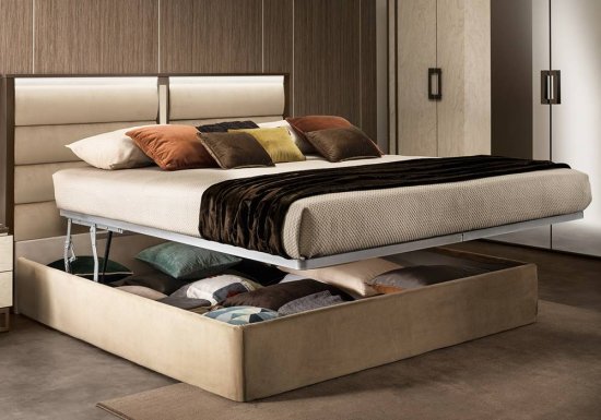 Κρεβάτι το οποίο είναι σχεδιασμένο σε χρώμα εκρού και διακοσμημένο με μεταλλικές καφέ λεπτομέρειες. Διαθέτει κεφαλάρι ντυμένο με ύφασμα.