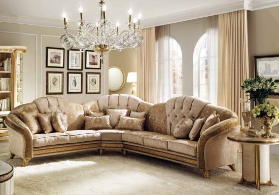 Γωνιακός καναπές ο οποίος είναι σχεδιασμένος σε χρώμα μπεζ και διακοσμημένος με χρυσά πόδια και χρυσές λεπτομέρειες.