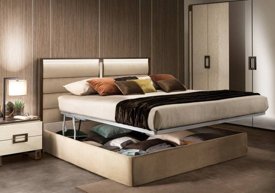 Κρεβάτι το οποίο είναι σχεδιασμένο σε χρώμα εκρού και διακοσμημένο με καφέ μεταλλικές λεπτομέρειες. Διαθέτει κρυφό φωτισμό και αποθηκευτικό χώρο.