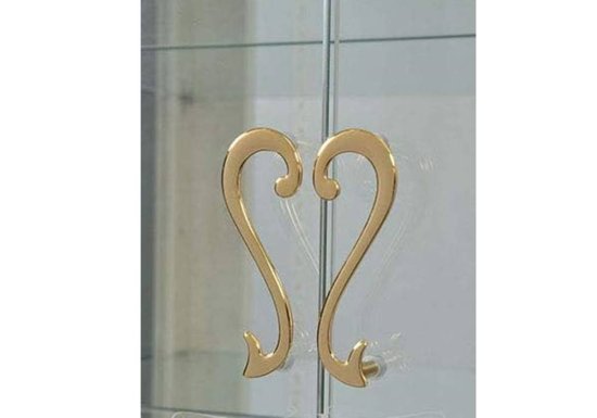 Δίφυλλη χαμηλή γυάλινη βιτρίνα σε χρώμα ιβουάρ με χρυσό πόμολο σε σχήμα καρδιάς.